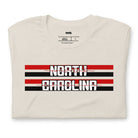 "North Carolina" in bold red and white text on a black and red striped background across the chest on a beige shirt.