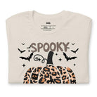 Beige t-shirt featuring a leopard-print pumpkin and "Spooky Vibes" text surrounded by bats, perfect for Halloween and fall season style.