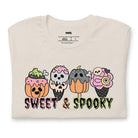 Beige t-shirt featuring a fun 'Sweet & Spooky' design with Halloween-themed ice cream cones, skulls, pumpkins, and spooky treats.