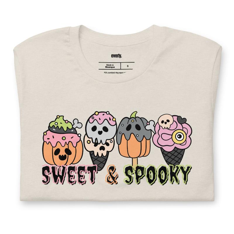 Beige t-shirt featuring a fun 'Sweet & Spooky' design with Halloween-themed ice cream cones, skulls, pumpkins, and spooky treats.