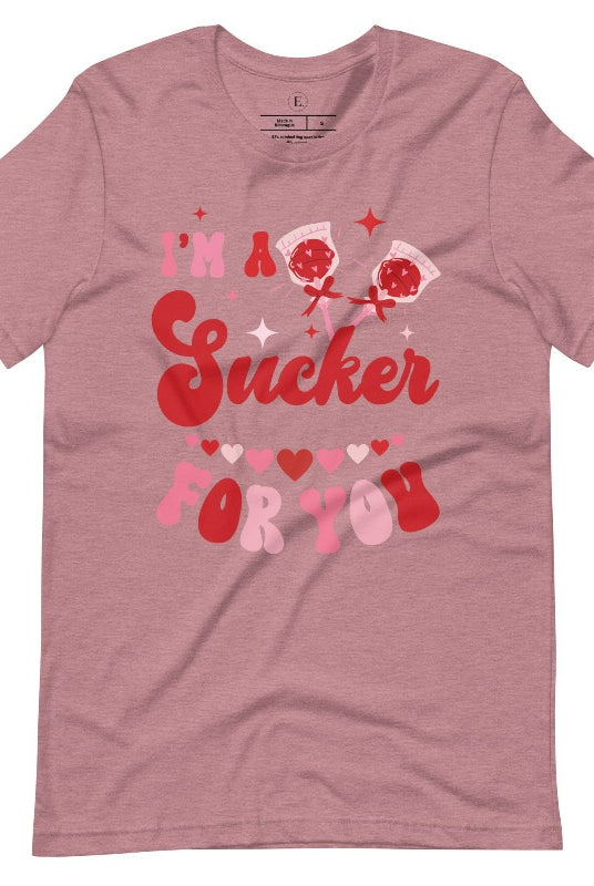 Indulge in the spirit of love with our Valentine's Day shirt! Adorned with charming Valentine lollipops and the playful saying, "I'm a sucker for you," on a heather orchid colored shirt. 