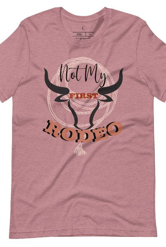 Unleash your cowboy spirit with our country western t-shirt boasting the statement "Not my First Rodeo" alongside bold bull horns and a lasso design on a heather orchid colored shirt. 