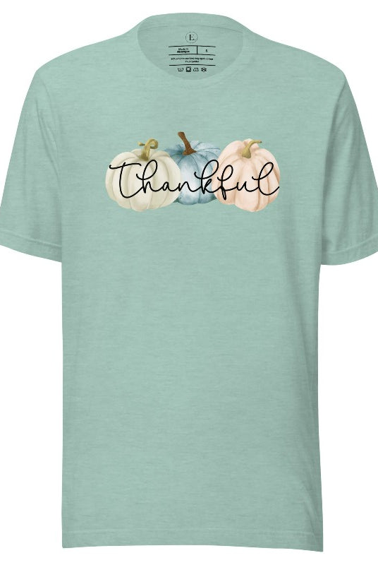 Express gratitude in style with our charming t-shirt. This design radiates autumn appreciation, featuring three pastel pumpkins and the word 'thankful' gracefully woven through the middle on a heather prism dusty blue colored shirt. 