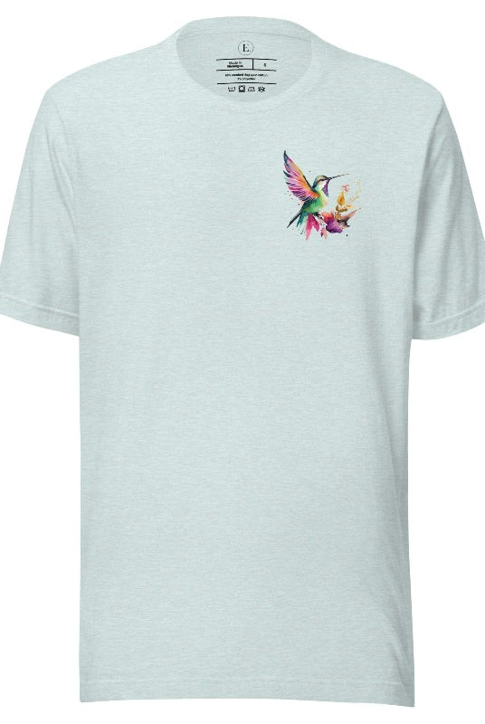 Elevate your style with our stunning t-shirt featuring a watercolor hummingbird delicately placed on the pocket on a heather prism ice blue shirt. 