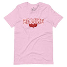 Elevate your Valentine's Day style with our "Be Mine" shirt! Featuring bold athletic lettering and three adorable hearts, on a heather prism lilac shirt. 