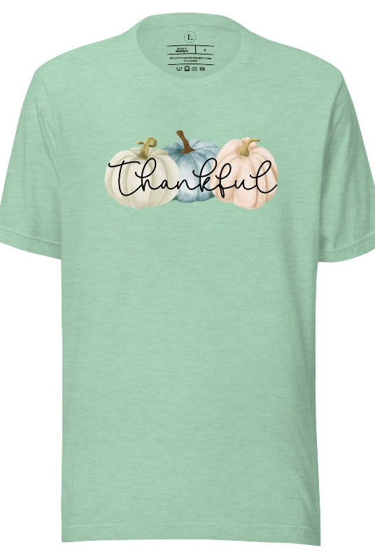 Express gratitude in style with our charming t-shirt. This design radiates autumn appreciation, featuring three pastel pumpkins and the word 'thankful' gracefully woven through the middle on a heather prism mint colored shirt. 