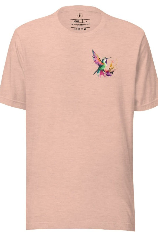 Elevate your style with our stunning t-shirt featuring a watercolor hummingbird delicately placed on the pocket on a heather prism peach shirt. 