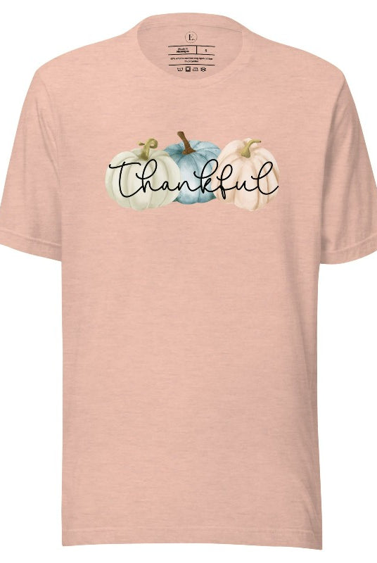 Express gratitude in style with our charming t-shirt. This design radiates autumn appreciation, featuring three pastel pumpkins and the word 'thankful' gracefully woven through the middle on a heather prism peach colored shirt. 