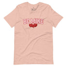 Elevate your Valentine's Day style with our "Be Mine" shirt! Featuring bold athletic lettering and three adorable hearts, on a heather prism peach shirt. 