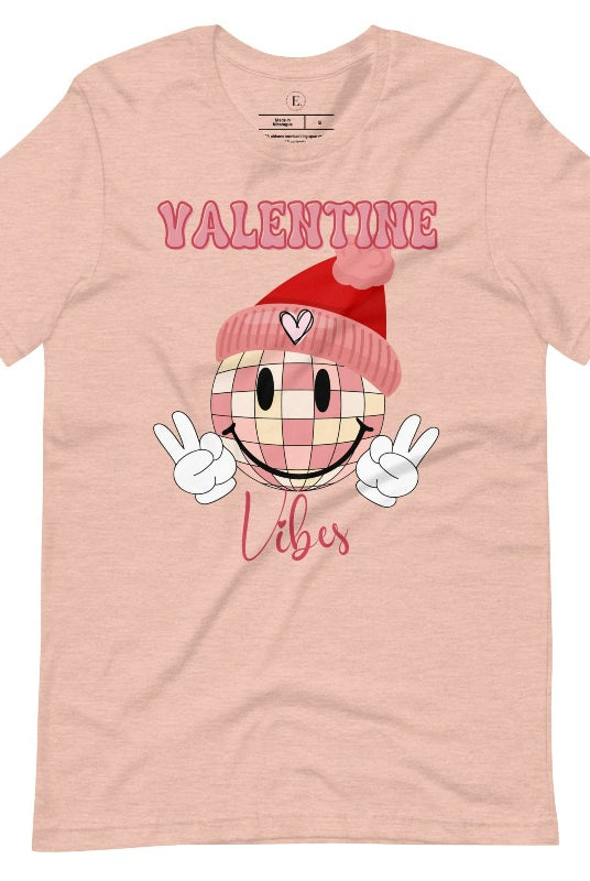 Get into the Valentine's Day spirit with our fun and funky shirt donning the words "Valentine Vibes" alongside a disco ball smiley face flashing peace fingers on a heather prism peach shirt. 