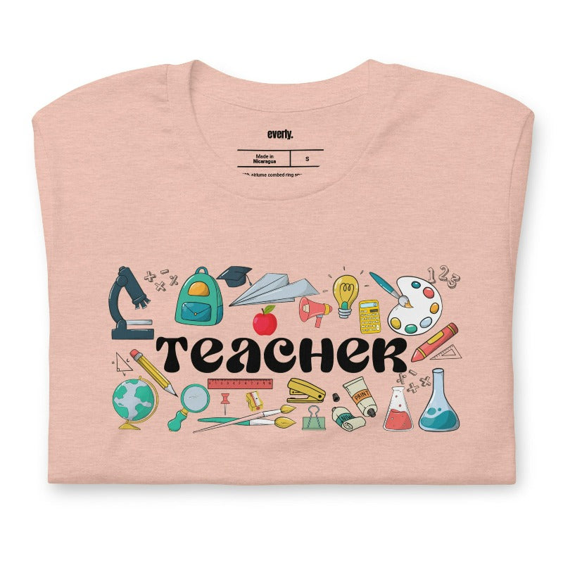 Teacher-themed graphic tee featuring the word 'Teacher' surrounded by all things related to teaching. Perfect for teacher shirts and teacher gifts. Peach graphic tees. 