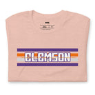 Bella + Canvas 3001 unisex shirt with Clemson University stripe design in purple, orange, and white, with "Clemson" written in bold letters on a heather prism peach graphic tee.