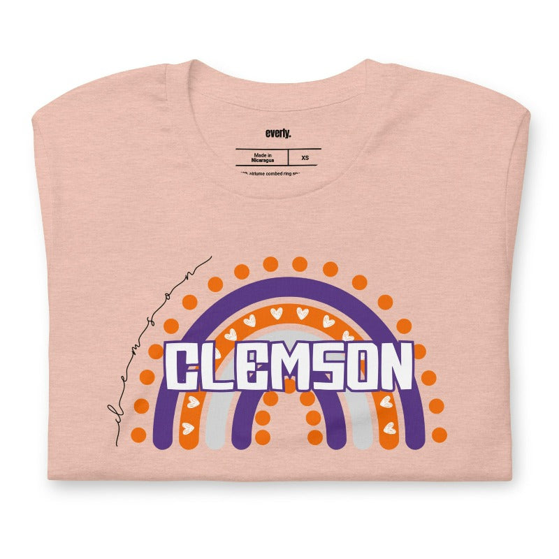 Bella + Canvas 3001 unisex shirt featuring a colorful rainbow design with the word "Clemson" in the center, representing Clemson University on a peach graphic tee.