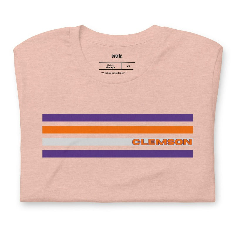 Bella + Canvas 3001 unisex T-shirt featuring a Clemson University design with purple, orange, and grey stripes and the word "Clemson" in bold orange letters on a peach shirt