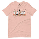 Peach t-shirt featuring a row of dogs dressed in ghost costumes with pumpkins, perfect for Halloween fun and dog lovers.