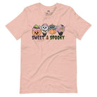 Peach t-shirt featuring a fun 'Sweet & Spooky' design with Halloween-themed ice cream cones, skulls, pumpkins, and spooky treats.