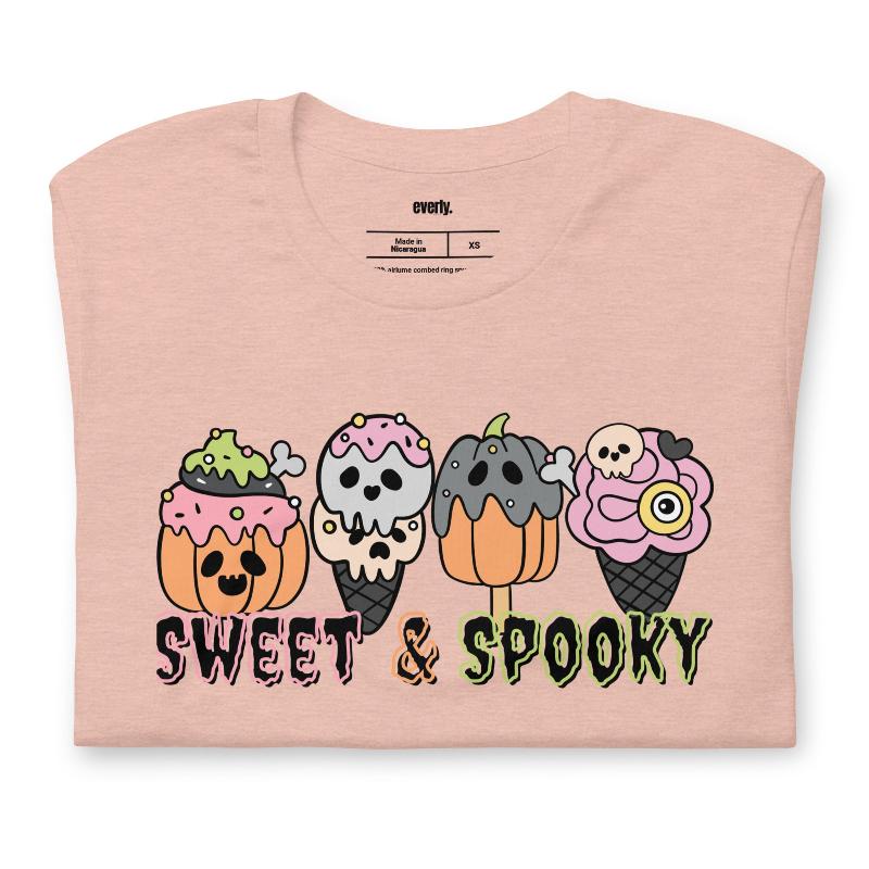 Peach t-shirt featuring a fun 'Sweet & Spooky' design with Halloween-themed ice cream cones, skulls, pumpkins, and spooky treats.