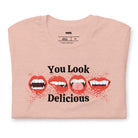 Peach t-shirt featuring a graphic of fanged red lips with the playful phrase "You Look Delicious" splattered in red, perfect for Halloween.