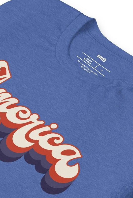 Close-up image of a USA July 4th graphic tee with the word 'America' spelled out in funky retro lettering on the front. This vintage-inspired tee is perfect for adding a fun and nostalgic touch to your Independence Day celebrations on a royal blue graphic tee.