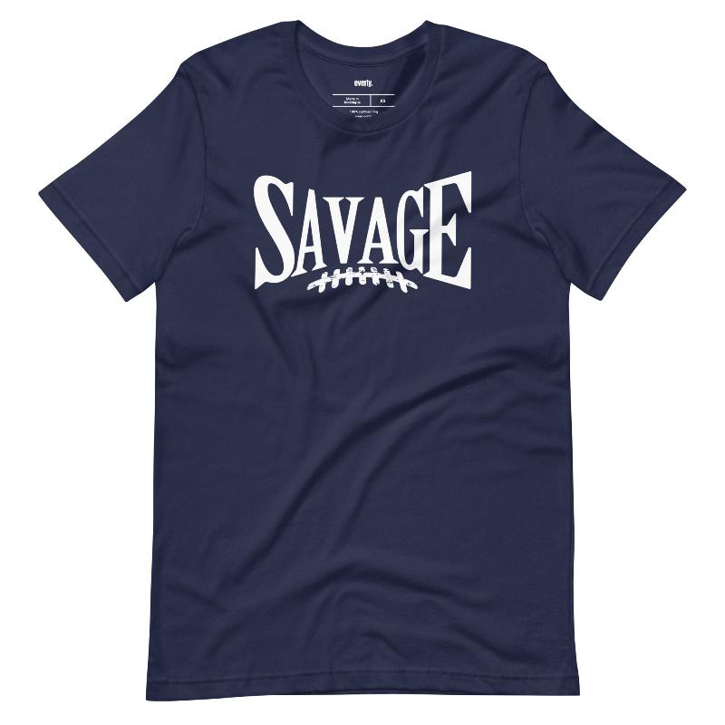 "Savage" in large, bold white letters with a football graphic underneath. The shirt is from Bella + Canvas and is made of 100% combed and ring-spun cotton on a navy shirt