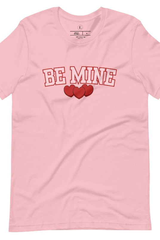 Elevate your Valentine's Day style with our "Be Mine" shirt! Featuring bold athletic lettering and three adorable hearts, on a pink shirt. 