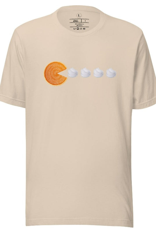 Level up your style with our playful t-shirt featuring a pumpkin pie shaped like Pac-Man devouring whipped cream swirls on a soft cream shirt. 