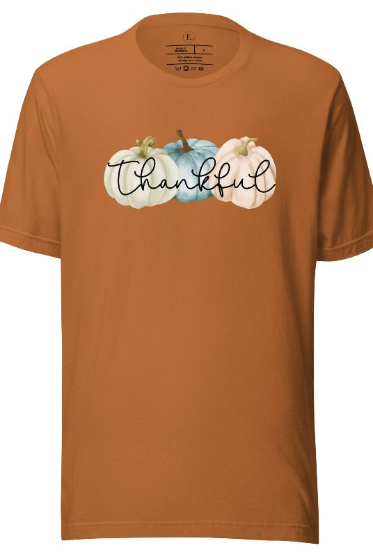Express gratitude in style with our charming t-shirt. This design radiates autumn appreciation, featuring three pastel pumpkins and the word 'thankful' gracefully woven through the middle on a toast colored shirt. 