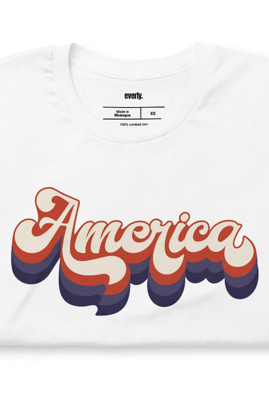 Close-up image of a USA July 4th graphic tee with the word 'America' spelled out in funky retro lettering on the front. This vintage-inspired tee is perfect for adding a fun and nostalgic touch to your Independence Day celebrations on a white graphic tee. 