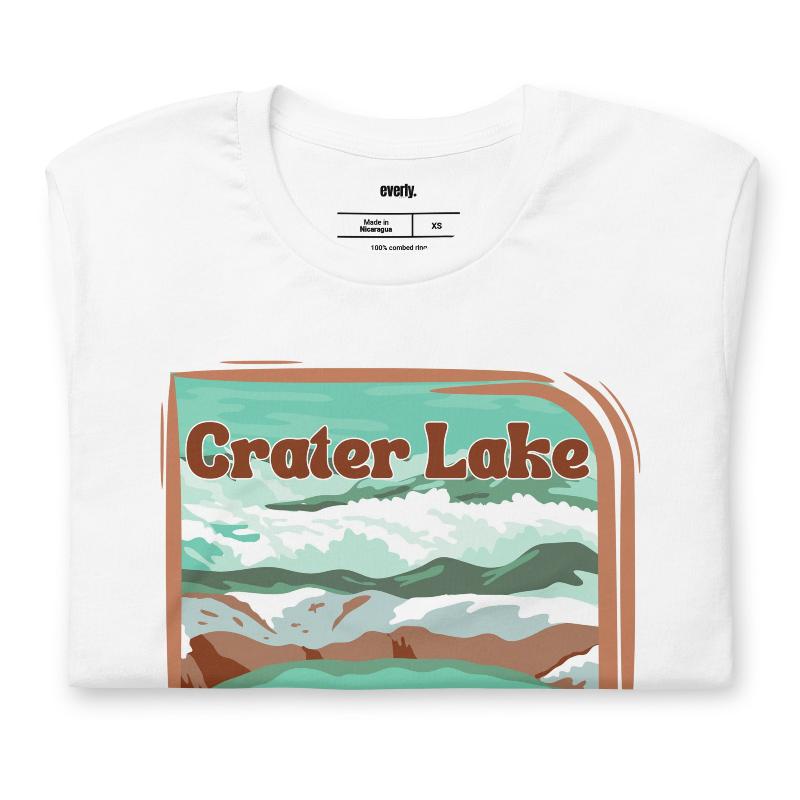 a colorful graphic of Crater Lake National Park, featuring mountains, water, and the text "Crater Lake National Park Oregon 1902 on a white shirt. 