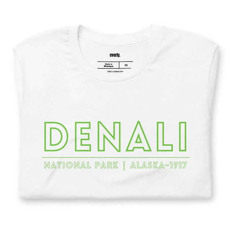 White Bella + Canvas 3001 t-shirt with front and back Denali National Park designs. The front features "Denali National Park | Alaska - 1917" in neon green text, and the white showcases a colorful, detailed illustration of Denali's landscapes and wildlife.