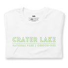 A vibrant design of Crater Lake National Park on the back, showcasing the lake and surrounding mountains in colorful hues, with the text "Crater Lake National Park | Oregon 1902" on the front. This design is on a white shirt. 