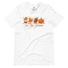  'Tis The Season' design with fall-themed graphics including a cupcake, maple leaf, football, and pumpkin, surrounded by falling leaves on a white shirt. 