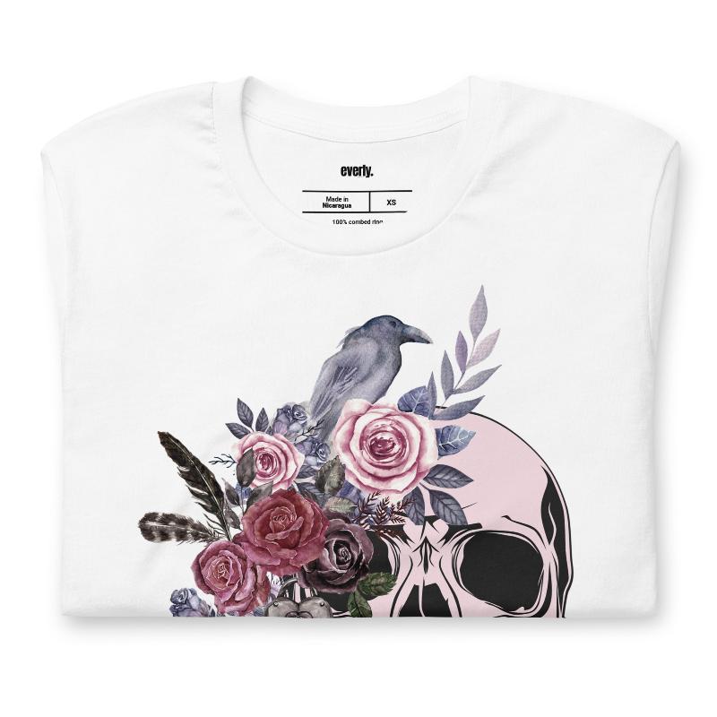 A Halloween-themed design with a skull adorned with flowers and a raven, accompanied by the text "Be Original." The shirt is soft and perfect for celebrating Halloween in style on a white shirt.