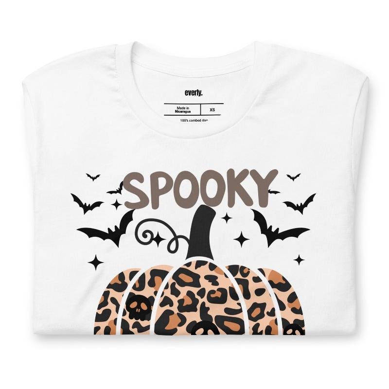 White t-shirt featuring a leopard-print pumpkin and "Spooky Vibes" text surrounded by bats, perfect for Halloween and fall season style.