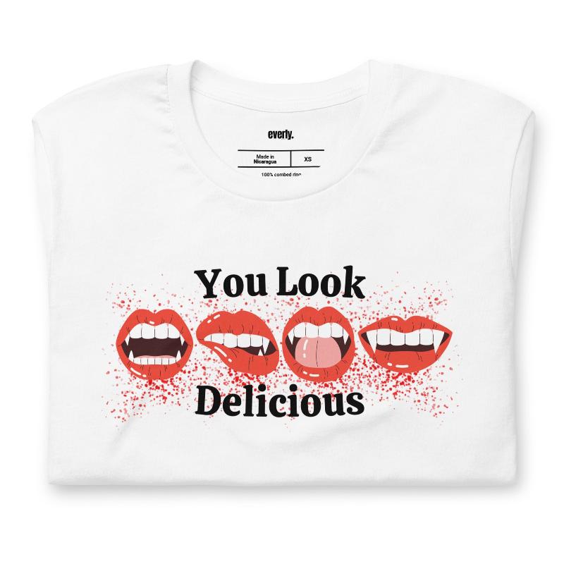 White t-shirt featuring a graphic of fanged red lips with the playful phrase "You Look Delicious" splattered in red, perfect for Halloween.